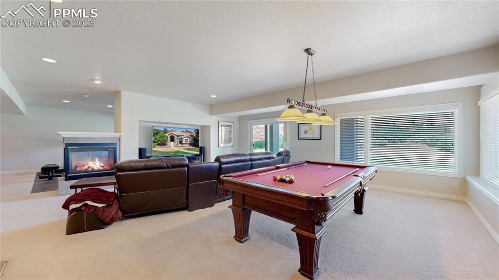 Image 26 of 46: Playroom featuring billiards table, light carpet, a glass covered fireplace