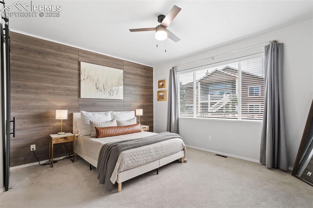 Image 10 of 22: Bedroom featuring wooden walls, an accent wall, light carpet, and a ceiling