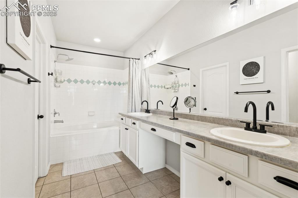 Image 12 of 22: Bathroom with tile patterned floors, tiled shower / bath combo, and double