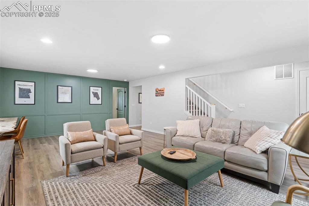 Image 15 of 22: Living room with wood finished floors, stairway, recessed lighting, and a d