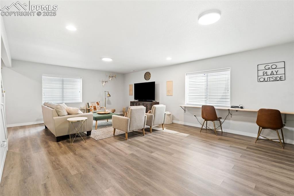 Image 16 of 22: Living room with light wood-style flooring and recessed lighting