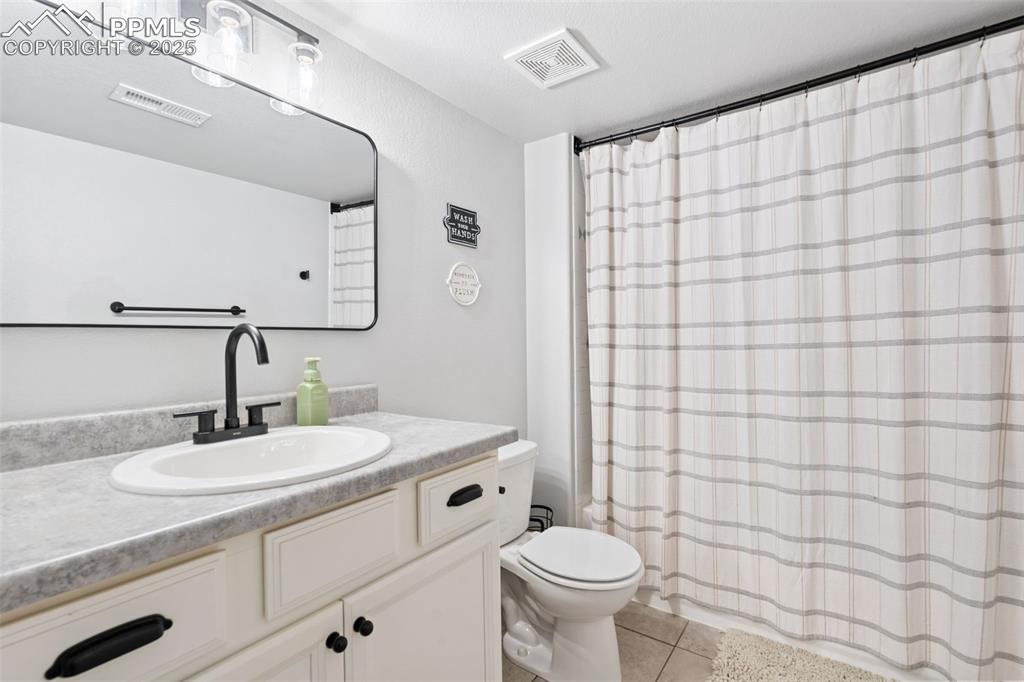 Image 18 of 22: Bathroom with vanity, tile patterned floors, and curtained shower