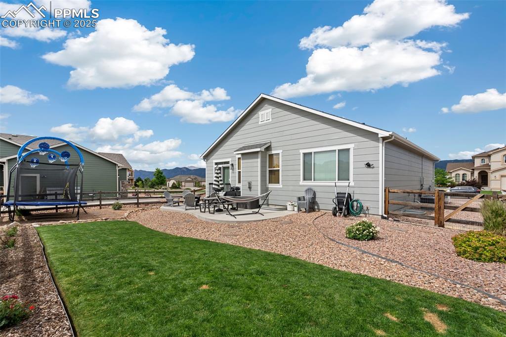 Image 22 of 22: Rear view of house featuring a trampoline, a patio area, a fenced backyard,