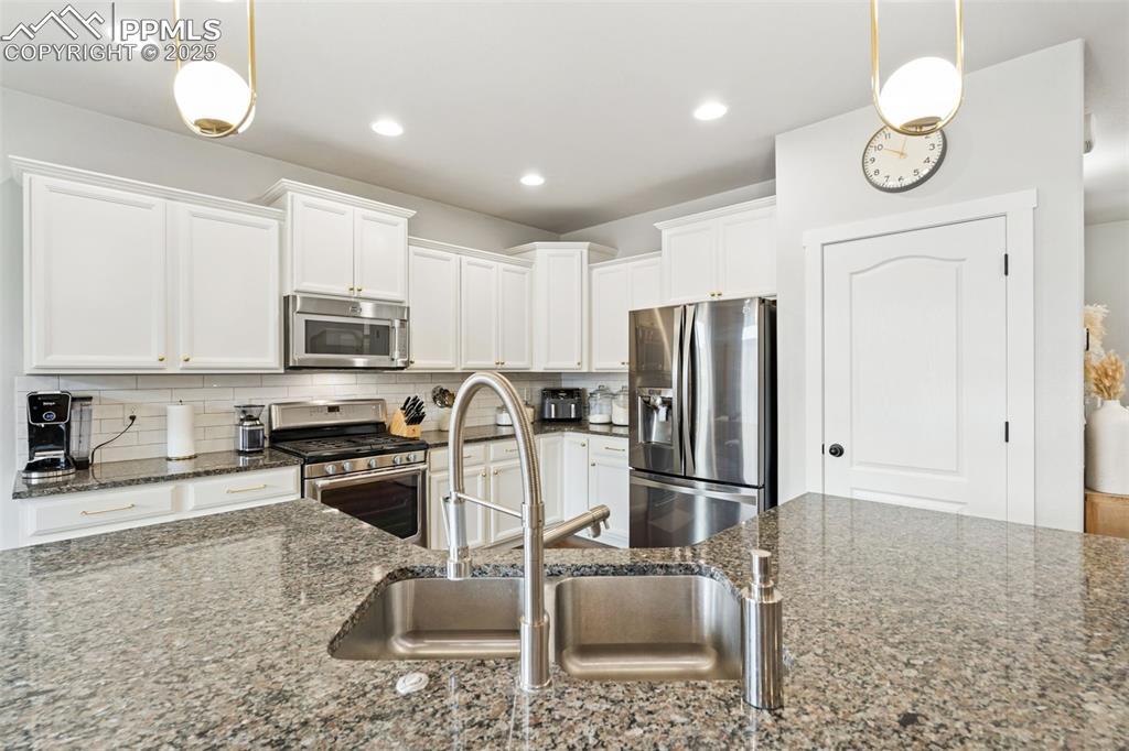 Image 9 of 22: Kitchen featuring stainless steel appliances, white cabinets, decorative ba