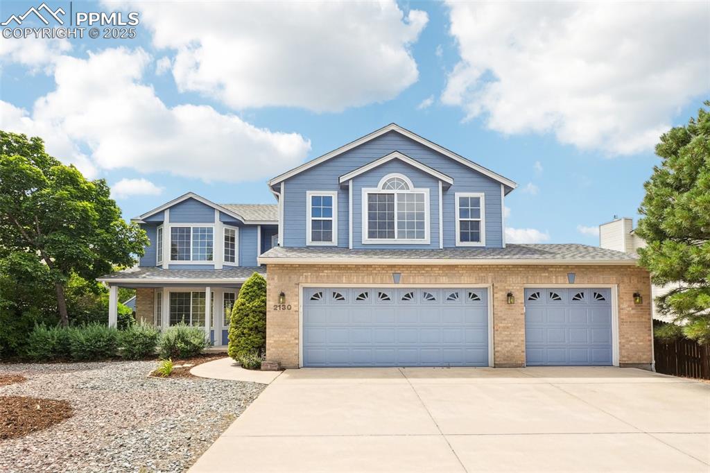 Caption: Traditional-style house featuring brick siding, concrete driveway, an attached garage, roof with shi