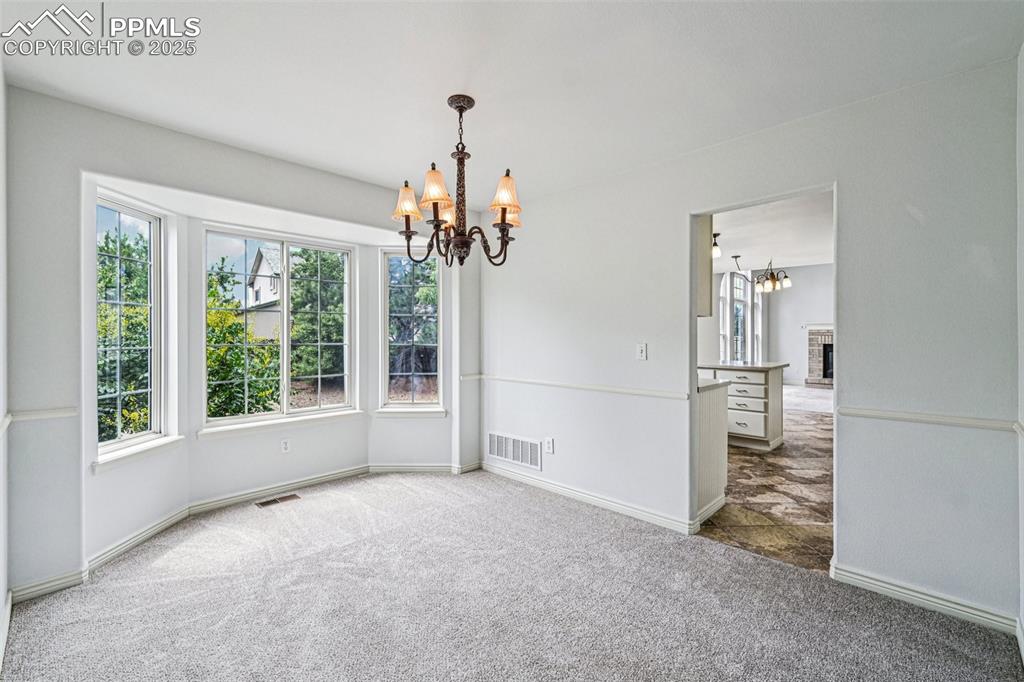Image 11 of 46: Carpeted empty room with a chandelier and a fireplace