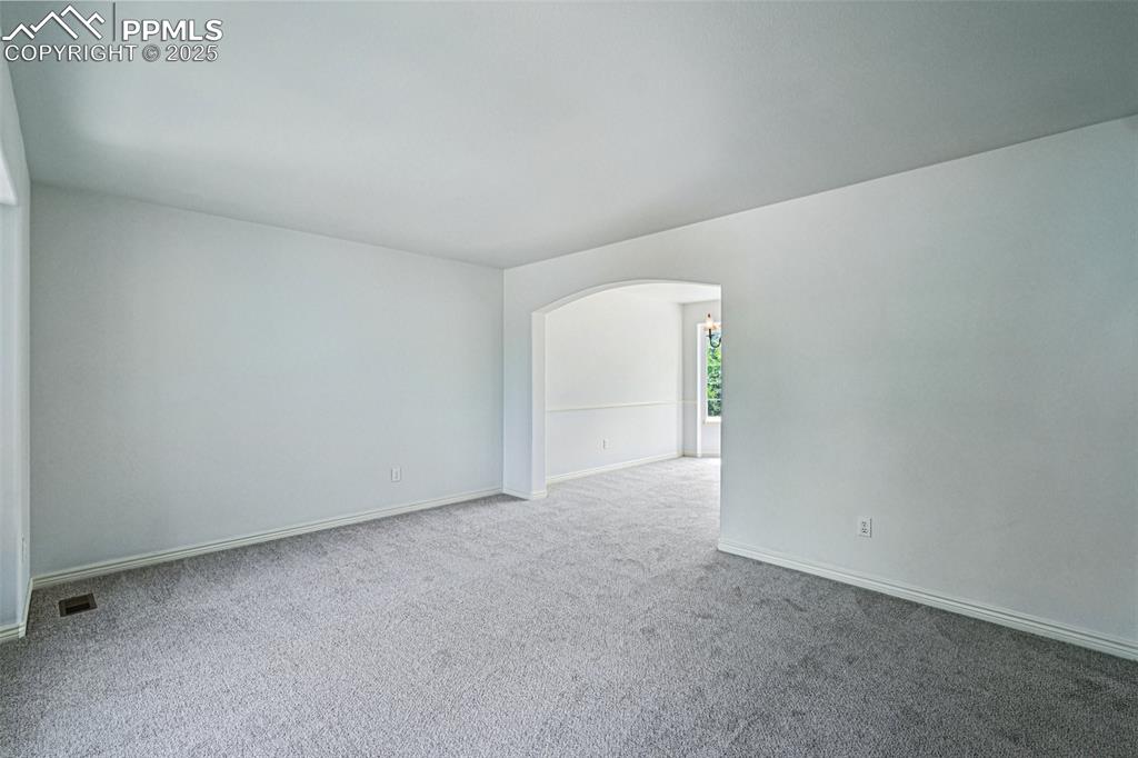 Image 14 of 46: Carpeted spare room with arched walkways and baseboards