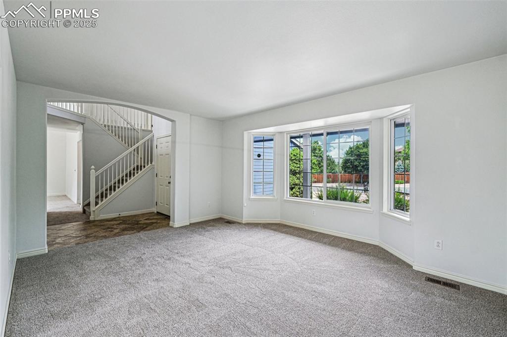 Image 15 of 46: Unfurnished living room with carpet flooring and stairway