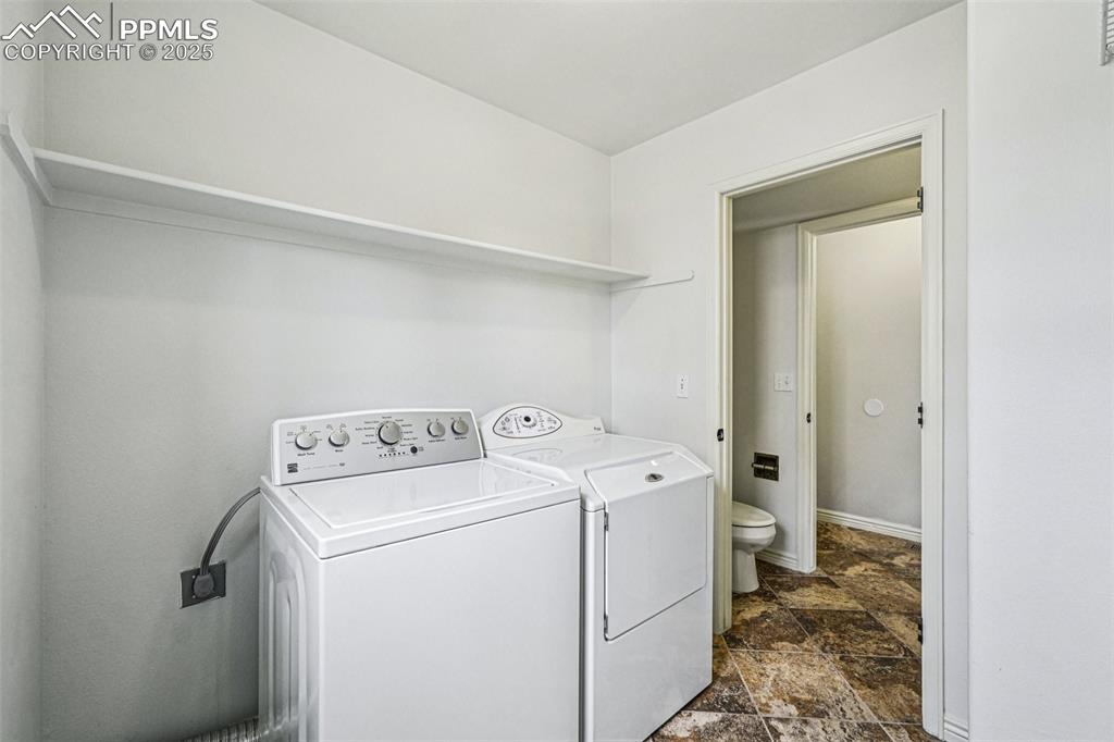Image 16 of 46: Washroom featuring stone finish flooring and washing machine and clothes dr