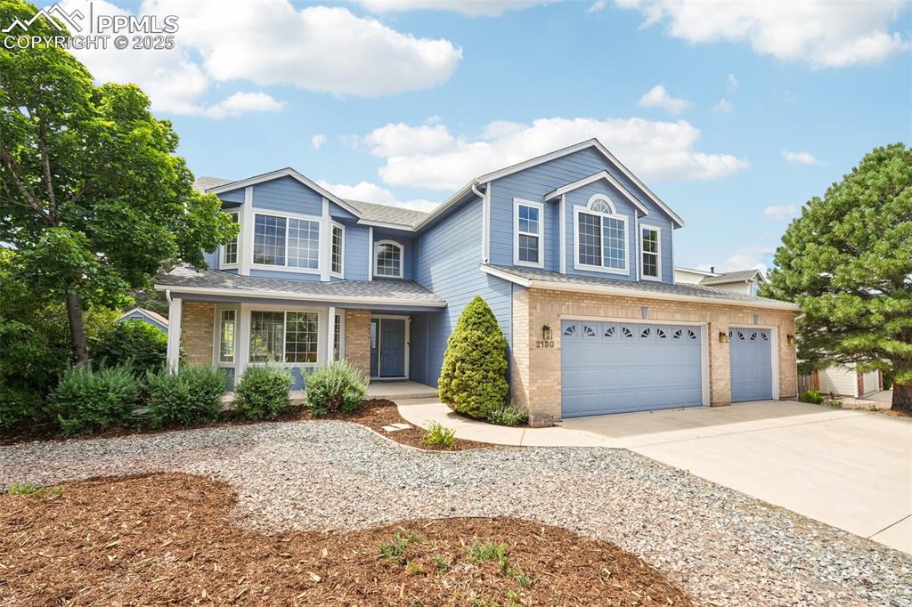 Image 2 of 46: Traditional home featuring concrete driveway, a garage, brick siding, a por