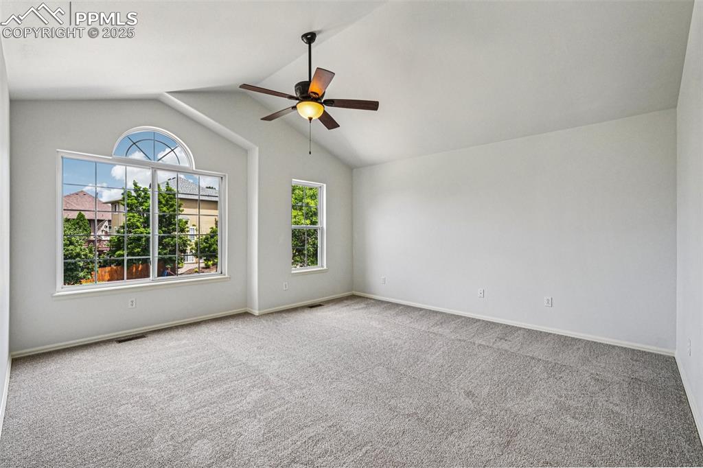 Image 21 of 46: Carpeted spare room with lofted ceiling and a ceiling fan