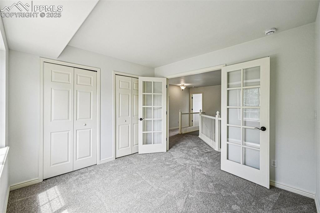Image 25 of 46: Unfurnished bedroom with french doors, multiple closets, and carpet floors