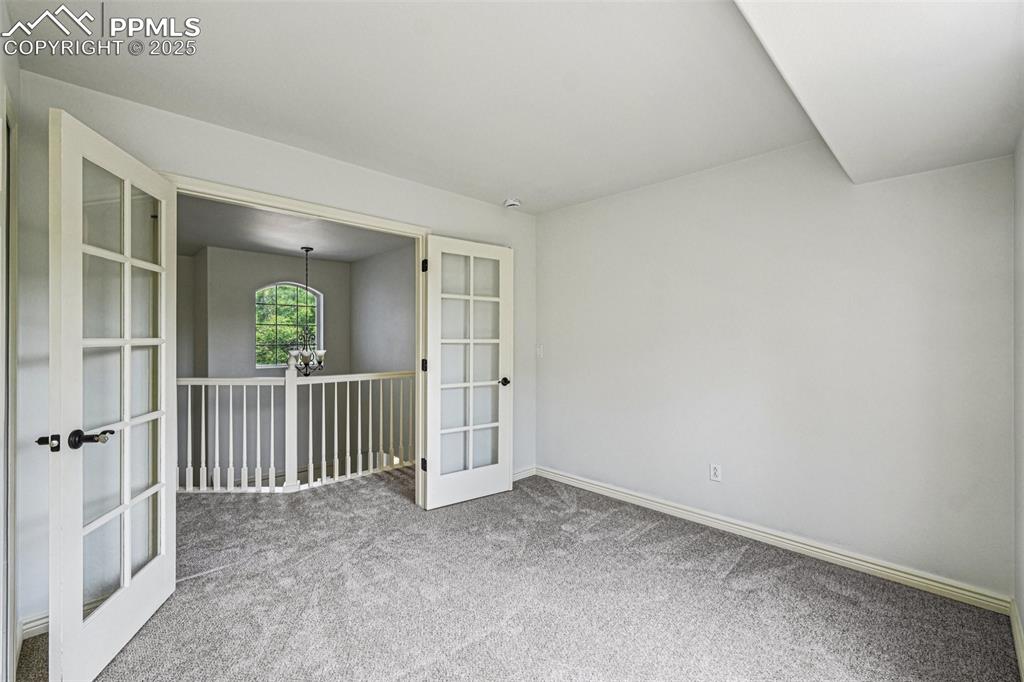 Image 26 of 46: Spare room featuring french doors, carpet floors, and a chandelier