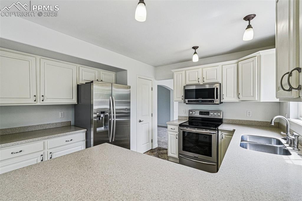 Image 9 of 46: Kitchen with stainless steel appliances, white cabinetry, and light counter
