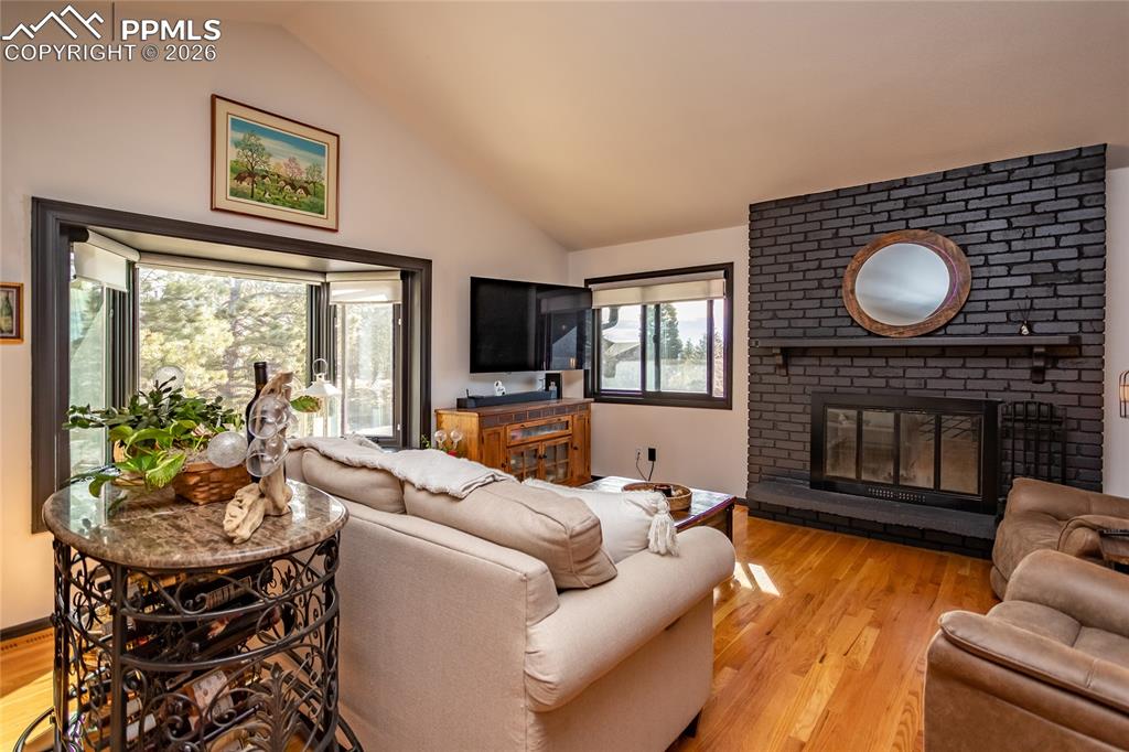 Image 12 of 50: Large windows let in the light & wood burning fireplace.