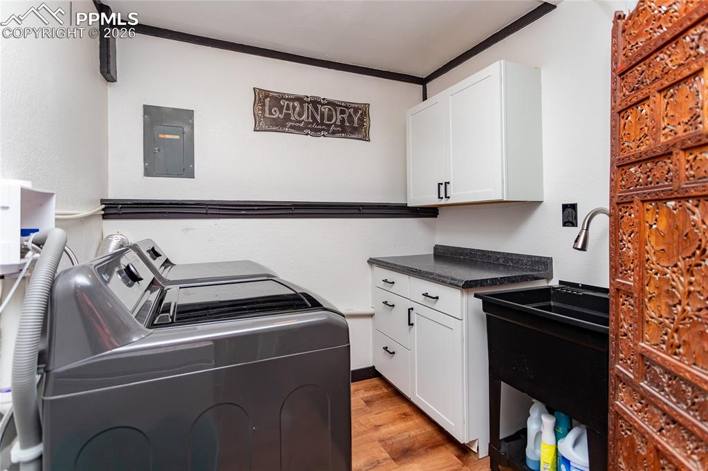 Image 48 of 50: Large laundry room with utility sink, folding area & storage.