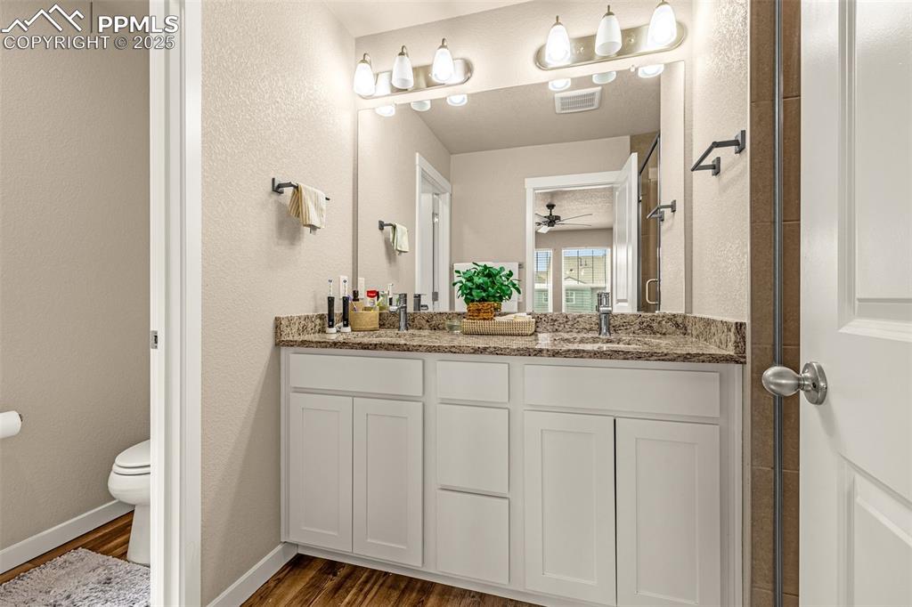 Image 13 of 35: Bathroom with dark wood-type flooring, a textured wall, and double vanity