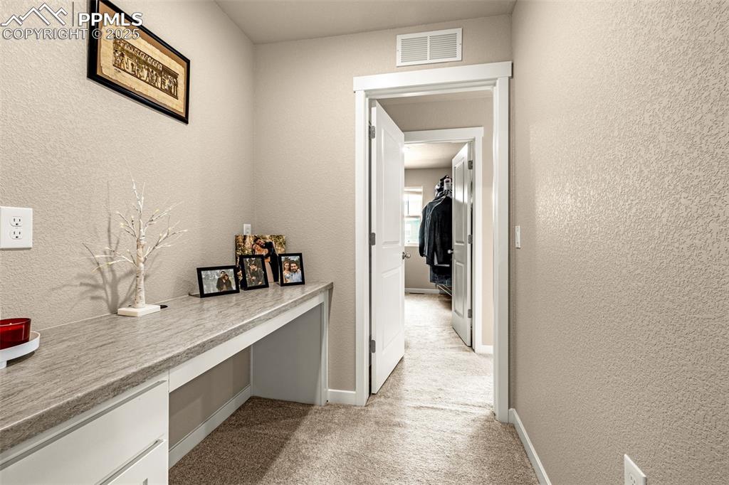 Image 15 of 35: Hall featuring a textured wall, an office area, and light carpet