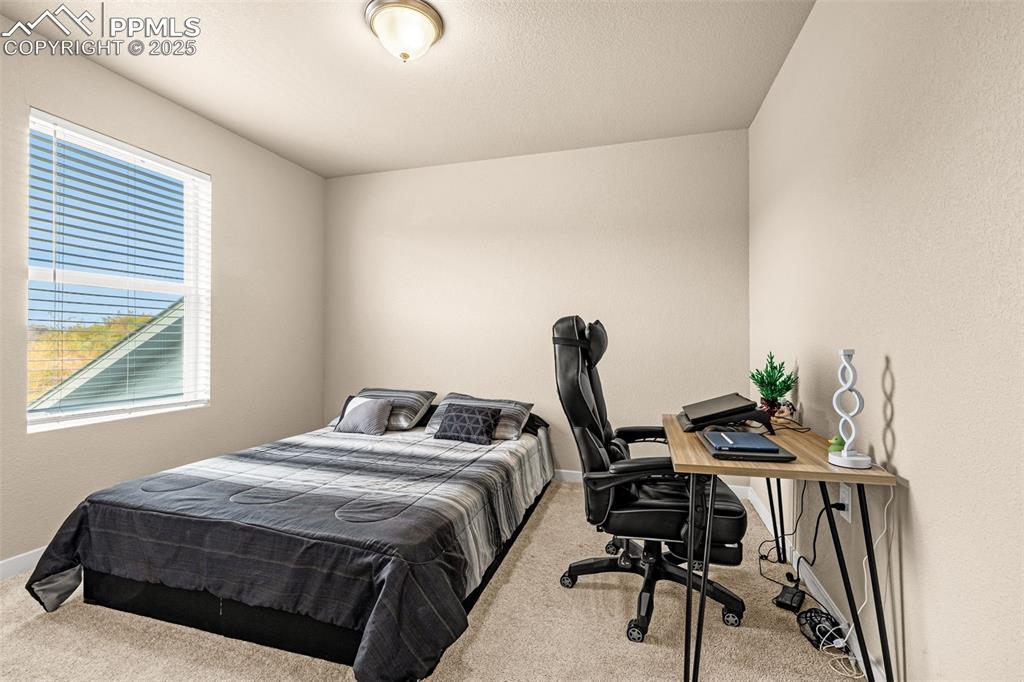 Image 17 of 35: Bedroom with light colored carpet and an office area