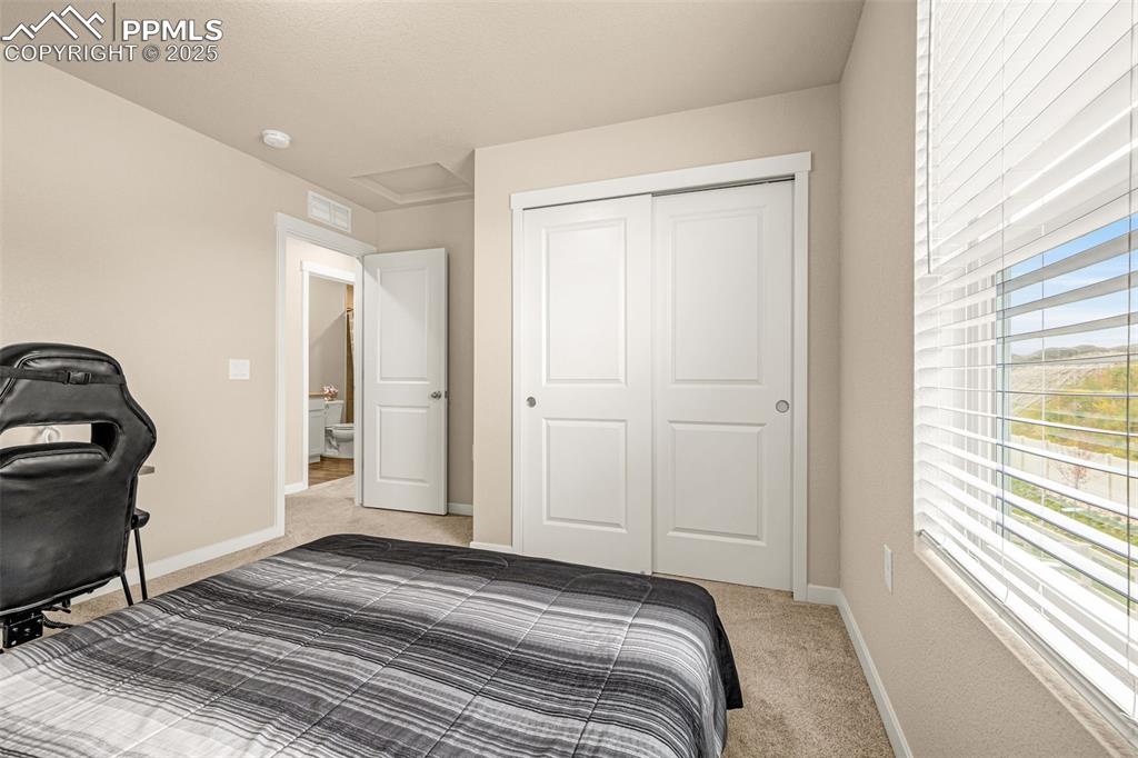 Image 18 of 35: Bedroom featuring light carpet, attic access, and a closet