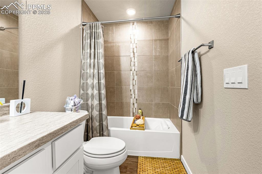 Image 20 of 35: Bathroom with a textured wall, shower / bath combination with curtain, vani