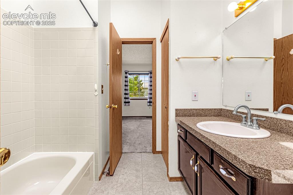 Image 15 of 32: Bathroom featuring a built-in bathtub with white tile surround, a dark wood