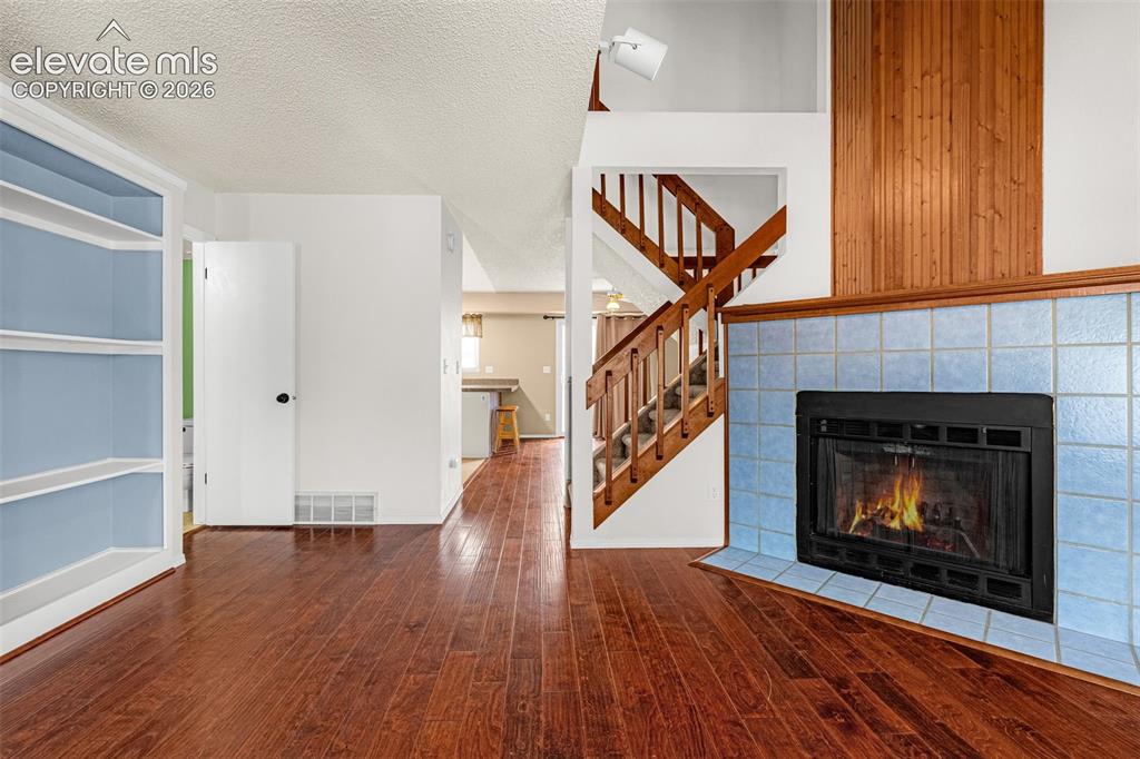 Image 4 of 32: Wood-finish flooring throughout, built-in shelving, fireplace with light bl
