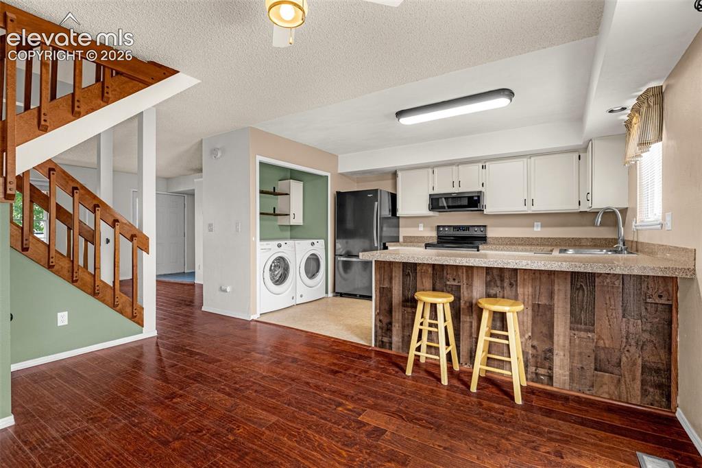 Image 7 of 32: Wood-finish flooring throughout, wood staircase, kitchen featuring white ca