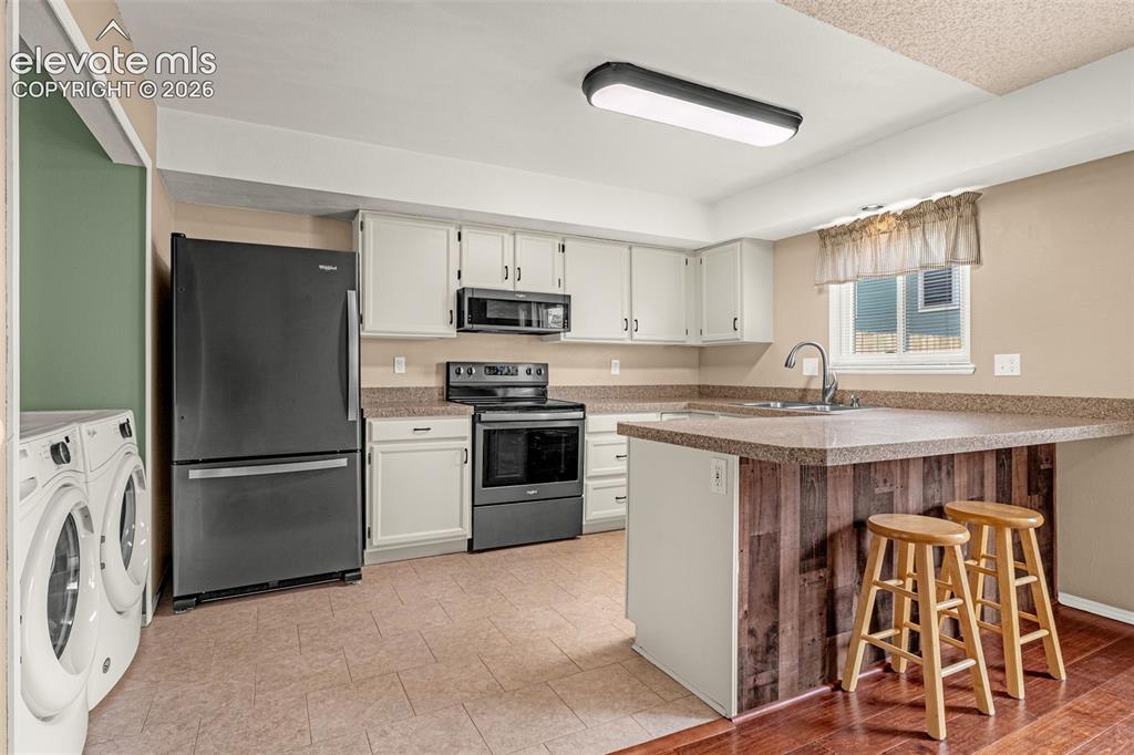 Image 9 of 32: Kitchen featuring white cabinetry, dark stainless steel appliances, a break