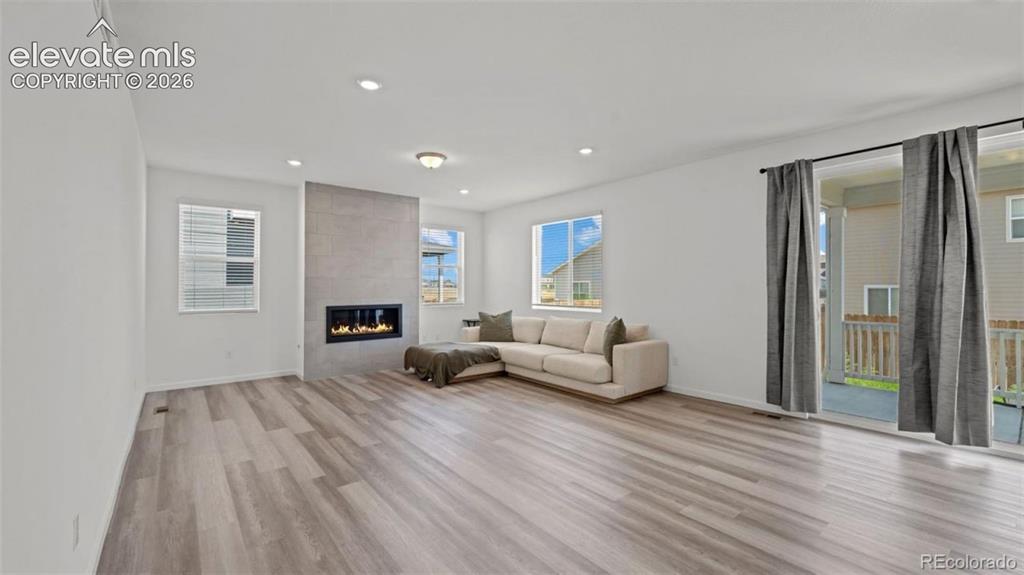 Image 13 of 38: Wood-finish flooring throughout, featuring a linear gas fireplace with a ti