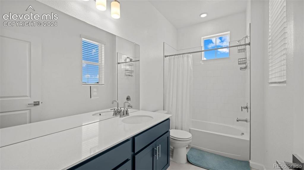 Image 16 of 38: White tile tub and shower combination with a single fixed showerhead