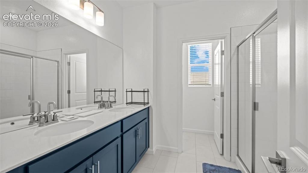 Image 17 of 38: Dual vanity with white countertop, chrome fixtures, and blue cabinetry