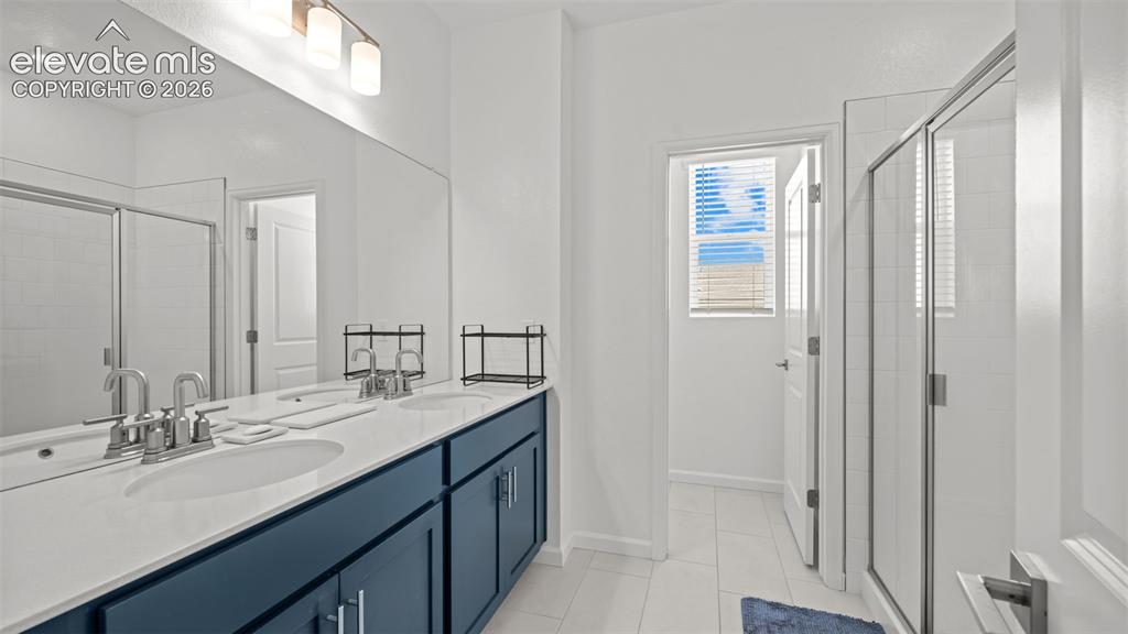 Image 18 of 37: Spa-inspired primary bathroom showcasing a dual-sink vanity with navy cabin