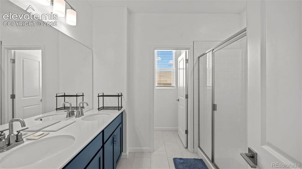 Image 19 of 38: Dual vanity with white countertop, chrome fixtures, and blue cabinetry