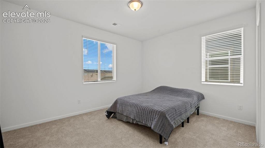 Image 23 of 38: Neutral wall finishes, carpeted flooring, two windows with blinds, and a fl