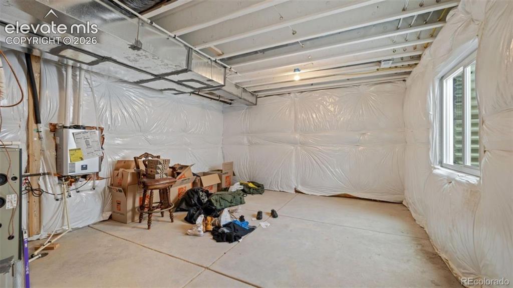Image 27 of 38: Unfinished basement with concrete flooring and exposed ceiling joists
