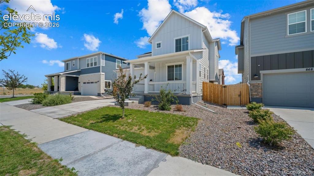 Image 3 of 38: Two-story residence featuring light gray siding with white trim, a covered 