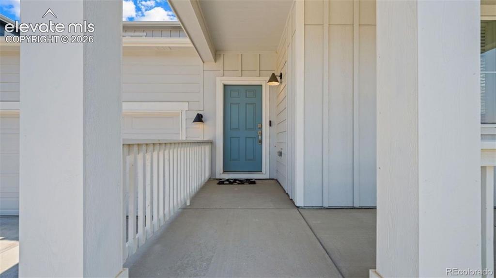 Image 4 of 38: Covered front porch with concrete flooring and white vertical railing