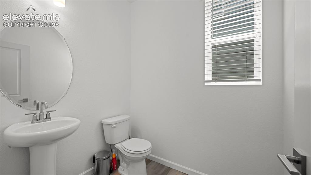 Image 6 of 37: Pedestal sink with chrome fixtures, oval mirror, window with blinds, and ne