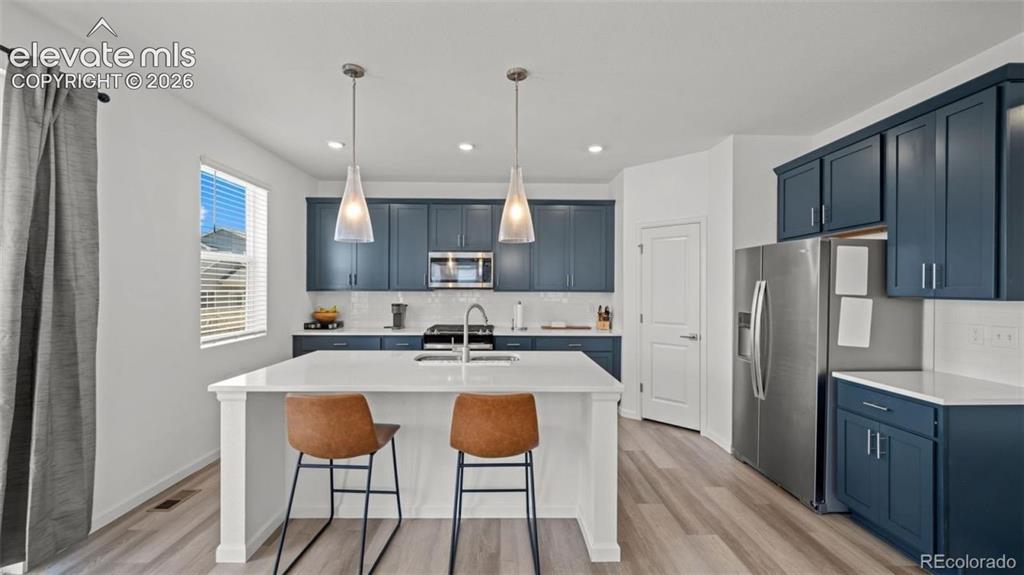 Image 7 of 38: Modern kitchen featuring custom cabinetry in deep blue with stainless steel