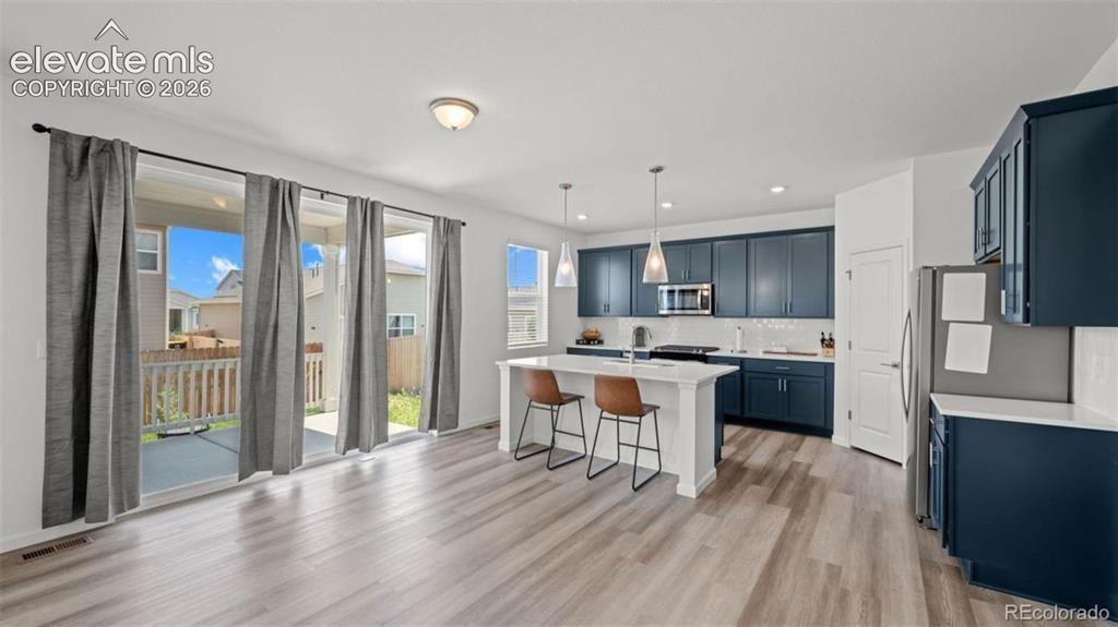 Image 9 of 38: Modern kitchen featuring dark blue cabinetry, stainless steel appliances, a