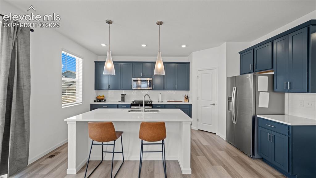 Image 9 of 37: Modern kitchen featuring a central island with seating, pendant lighting, s
