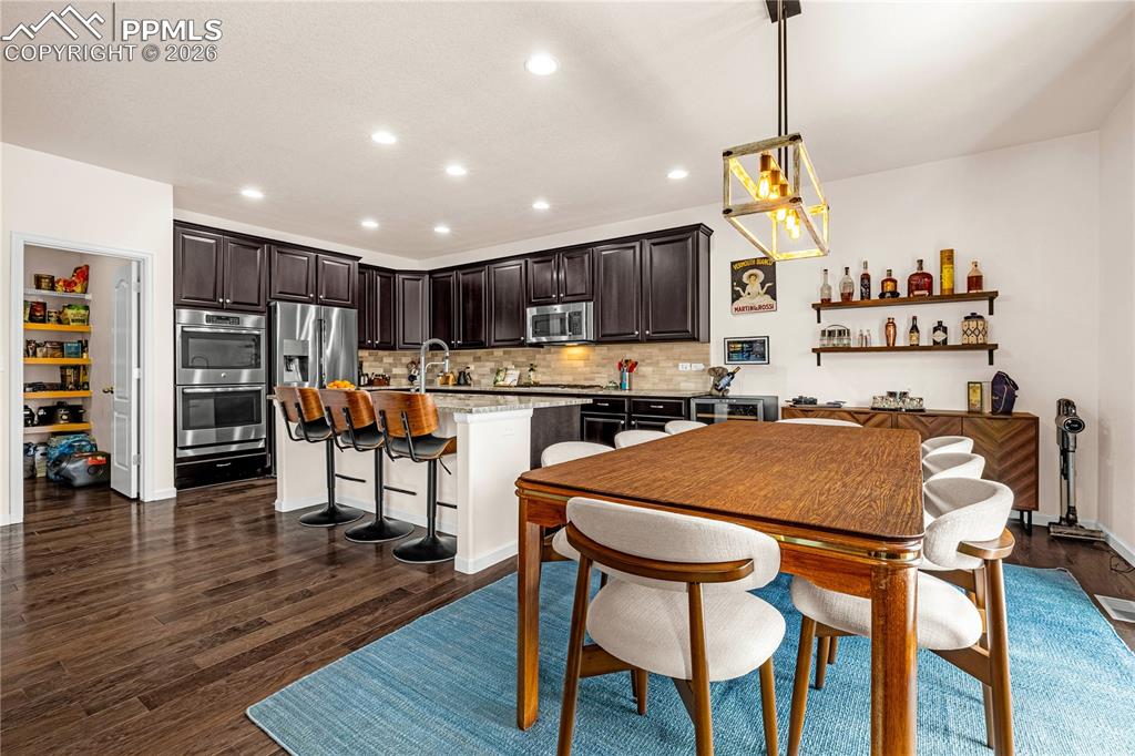 Image 11 of 37: Dining area with dark wood-style flooring and recessed lighting