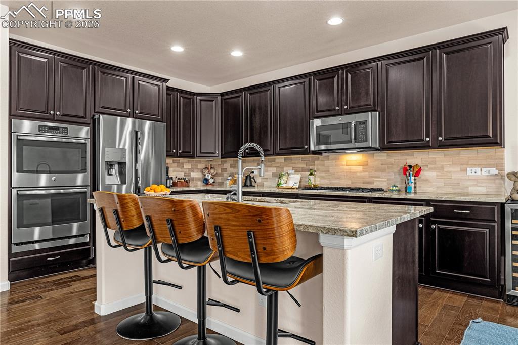Image 12 of 37: Kitchen featuring stainless steel appliances, dark wood-type flooring, a br