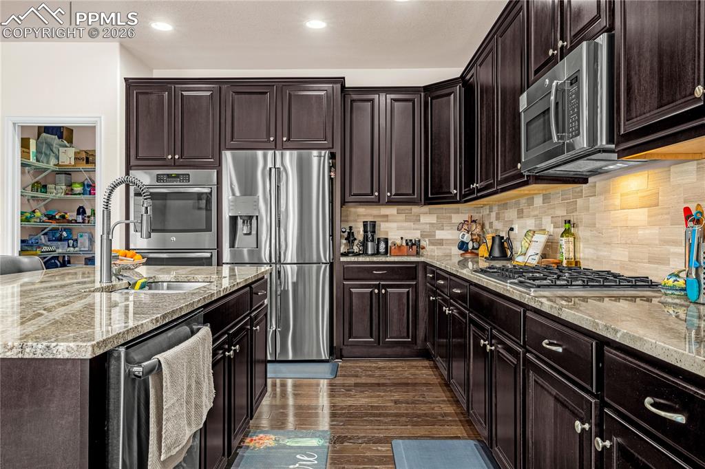 Image 13 of 37: Kitchen featuring dark wood finish cabinets, stainless steel appliances, li
