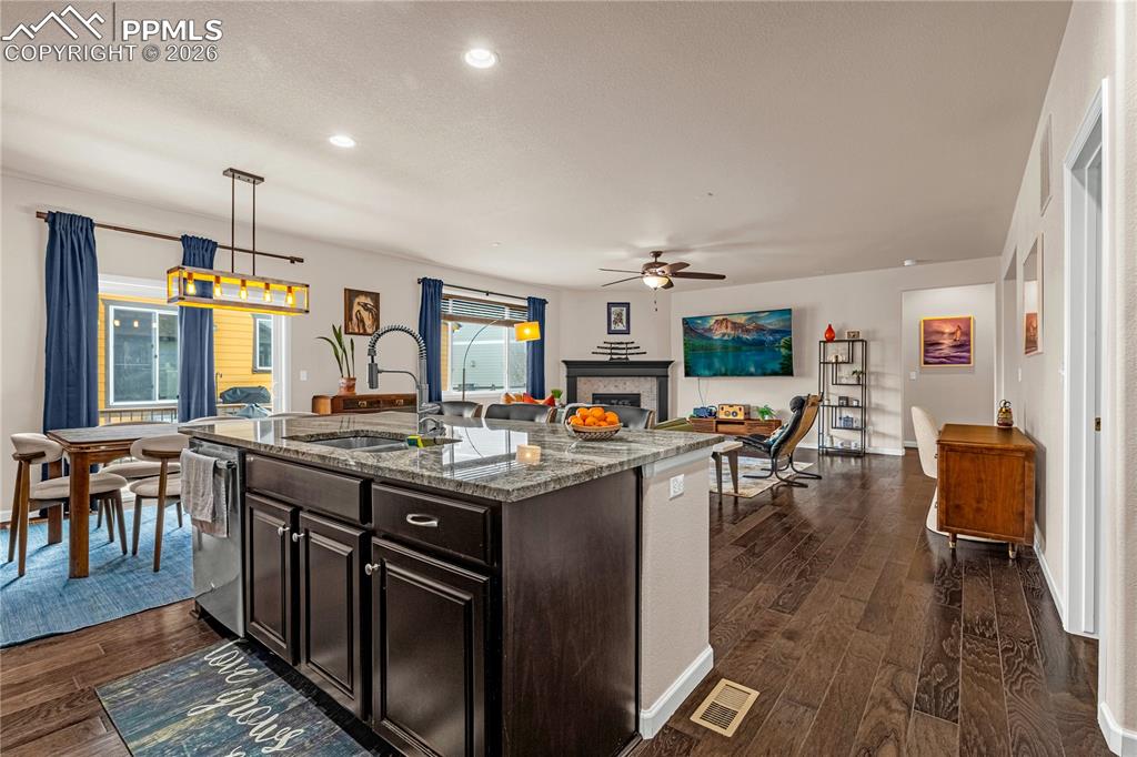 Image 14 of 37: Kitchen featuring dark wood finish cabinets, dark stone counters, dark wood