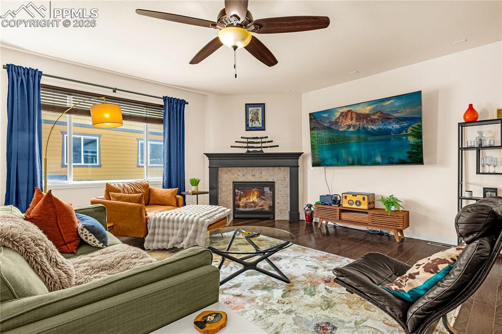 Image 6 of 37: Living room featuring wood finished floors, a ceiling fan, and a tile firep