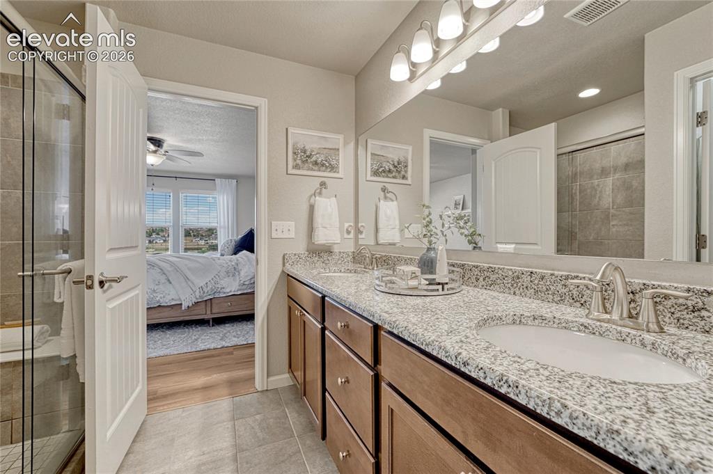 Image 20 of 47: The primary bathroom offers a spa-like feel with dual sinks, granite counte