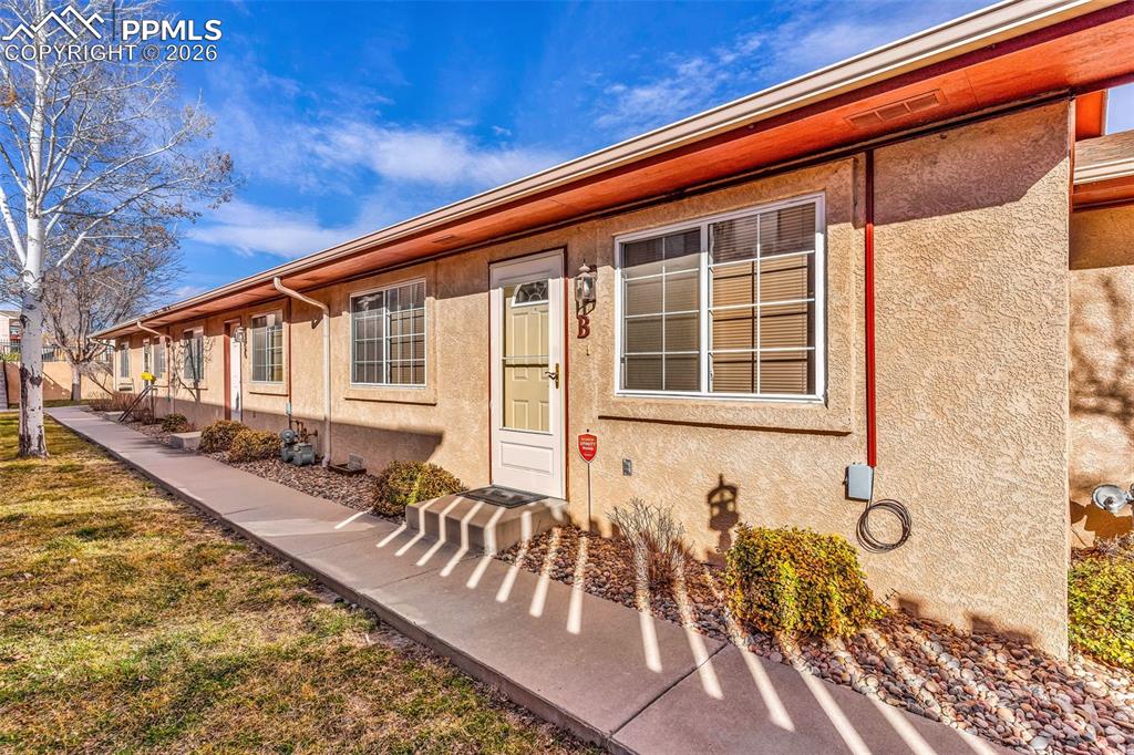 Image 3 of 28: Doorway to property featuring stucco siding and a yard