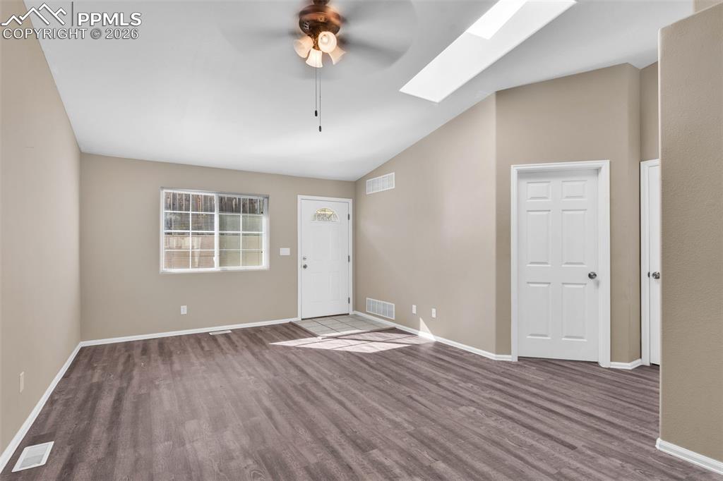 Image 6 of 28: Entryway featuring a skylight, vaulted ceiling, a ceiling fan, and dark woo